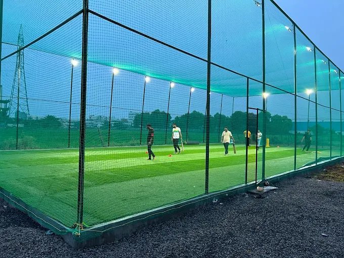 The floodlit turf at dusk, players warming up under the nets
